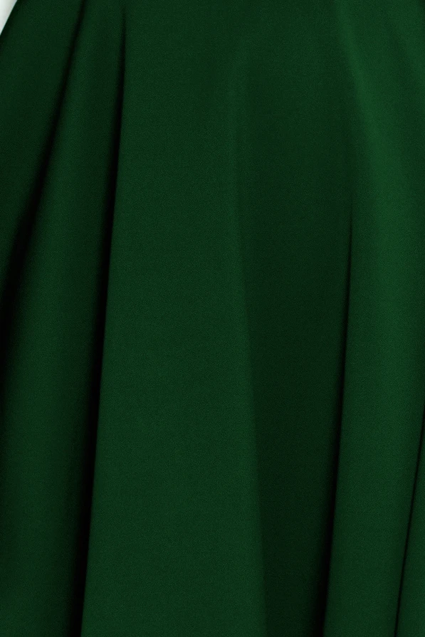 Zaļā kleita ar izplestu svārku daļu, kas piešķir elegantu un sievišķīgu izskatu. Audums ir gluds un viegli krītošs, radot plūstošu siluetu.