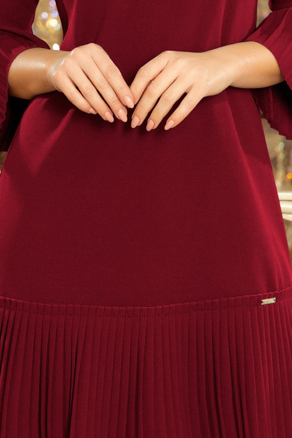 Sieviešu kleita tumši sarkanā krāsā ar plisētu apakšmalu un elegantiem, brīvi krītošiem piedurkņu galiem. Kleita izgatavota no mīksta un ērta materiāla, kas nodrošina komfortu un stilu.