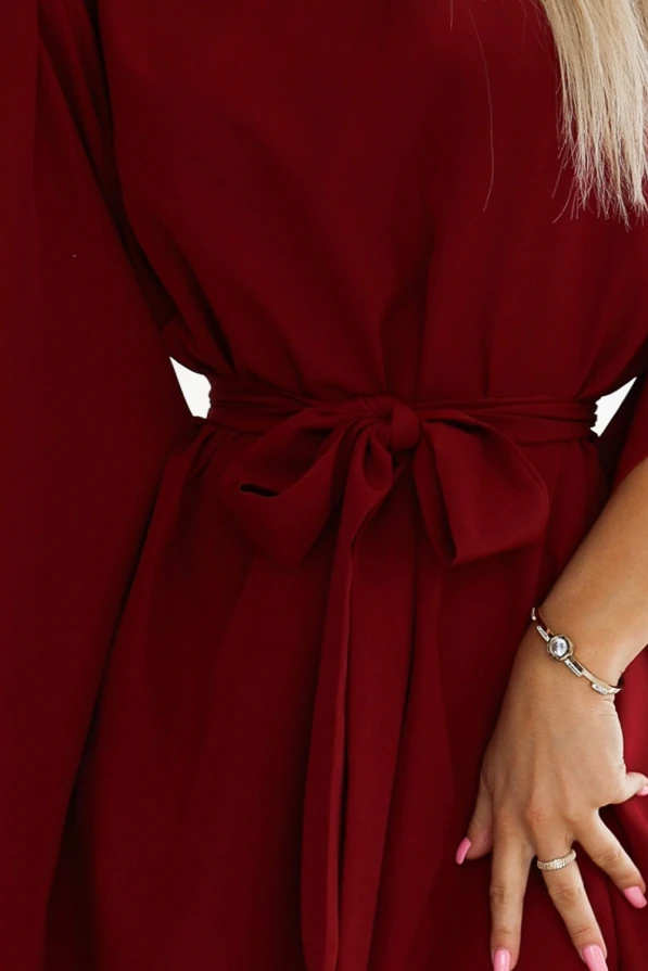 Sieviešu kleita sarkanā krāsā ar elegantu jostu, kas akcentē vidukli. Kleita ir izgatavota no plūstoša auduma, kas piešķir tai sievišķīgu un izsmalcinātu izskatu.