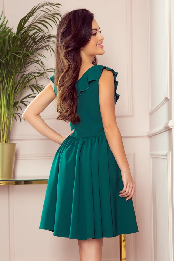 Zaļā kleita ar volāniem uz pleciem un pieguļošu augšdaļu, kas pāriet kuplā svārku daļā. Kleita ir eleganta un piemērota gan ikdienai, gan svinīgiem pasākumiem.