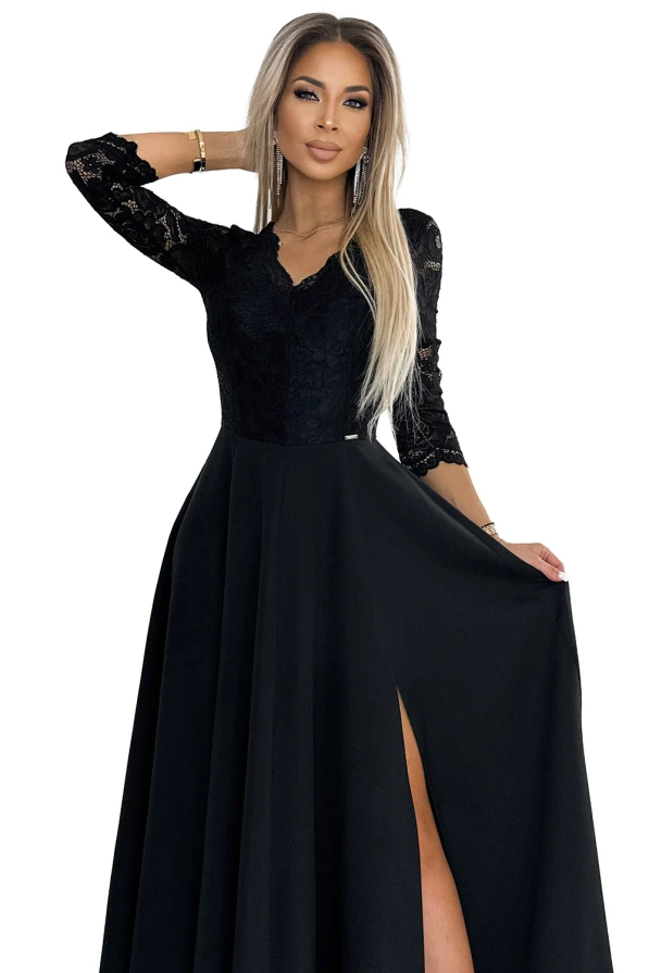 Eleganta melna kleita ar garām mežģīņu piedurknēm un dziļu šķēlumu svārku daļā. Kleita izceļas ar sievišķīgu siluetu un smalkām detaļām, kas piešķir tai izsmalcinātību.