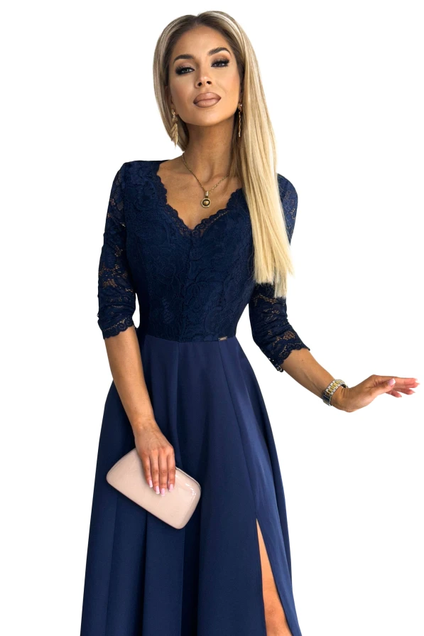 Eleganta tumši zila kleita ar mežģīņu augšdaļu un trīs ceturtdaļu piedurknēm. Kleitai ir elegants šķēlums un komplektā nāk ar smalku rokassomiņu.