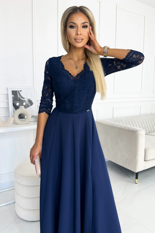 Eleganta tumši zila kleita ar mežģīņu augšdaļu un trīs ceturtdaļu piedurknēm, kas piešķir izsmalcinātu izskatu. Kleita ir garā griezuma, kas eleganti plūst līdz grīdai, radot klasisku un stilīgu siluetu.