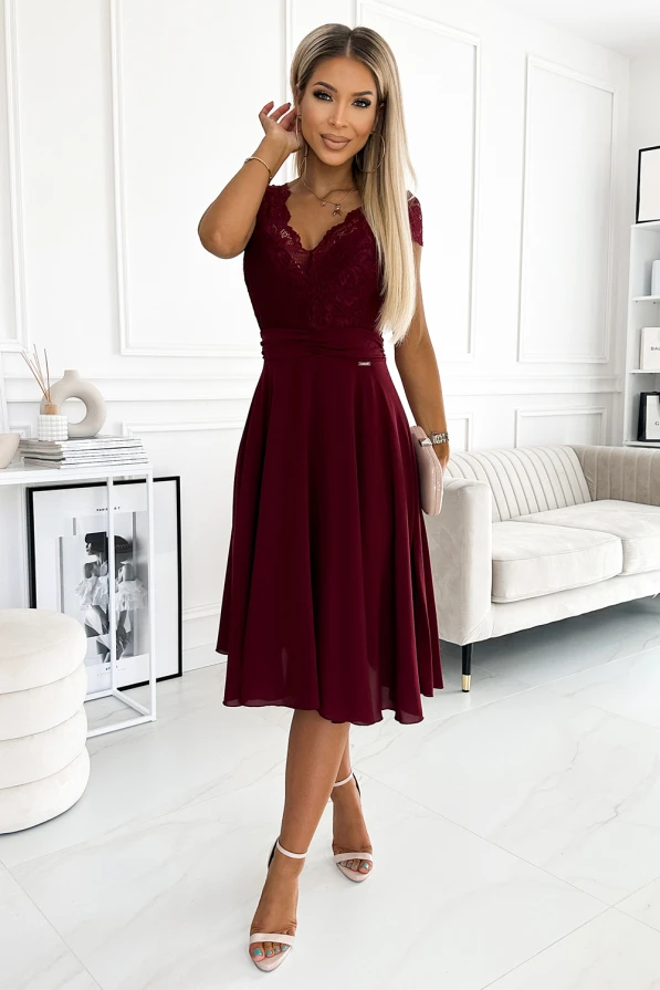 Eleganta šifona kleita bordo krāsā ar mežģīņu augšdaļu un īsām piedurknēm. Kleita ir vidēja garuma, ar plūstošu svārku daļu, kas piešķir tai graciozu izskatu.