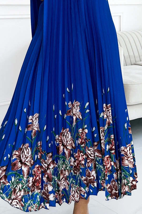 Zilā plisētā satīna kleita ar ziedu rakstu apakšmalā piešķir eleganci un krāšņumu. Ziedu motīvi brūnos un zaļos toņos piešķir kleitai dabisku un izsmalcinātu izskatu.
